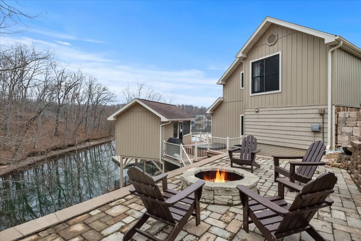 A welcoming lakeside fire pit area with comfortable seating is framed by water views and lush trees. The setting is cozy and tranquil, perfect for gathering, roasting marshmallows, and watching the sunset after a day outdoors.